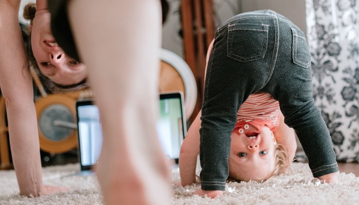 A mother does a virtual exercise class with her daughters in their living room