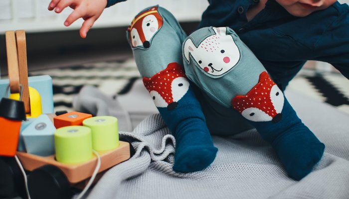 Toddler sitting on a blanket playing with wooden toys