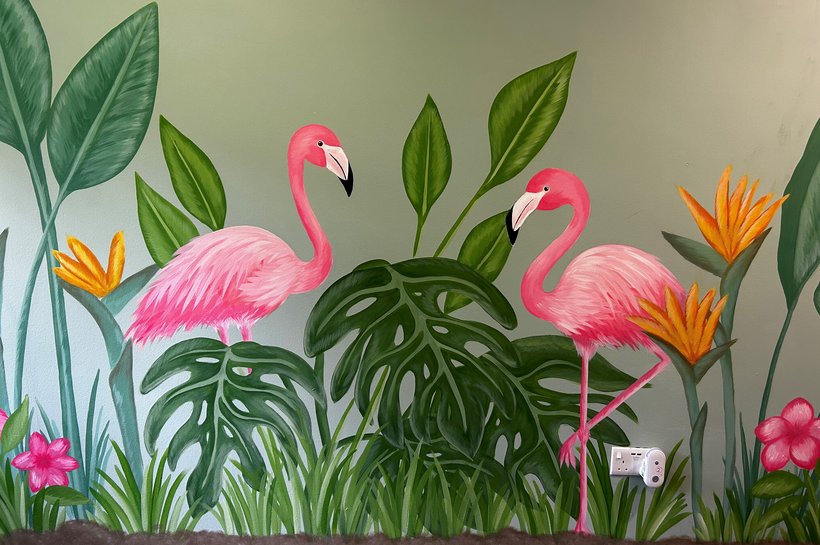 A wall with two flamingos painted on