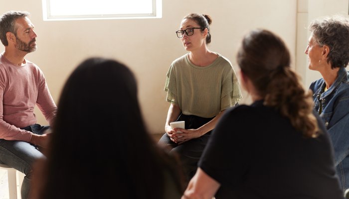 Adult woman talking to others in a support group sat in a circle