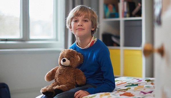Young boy in care with teddy bear