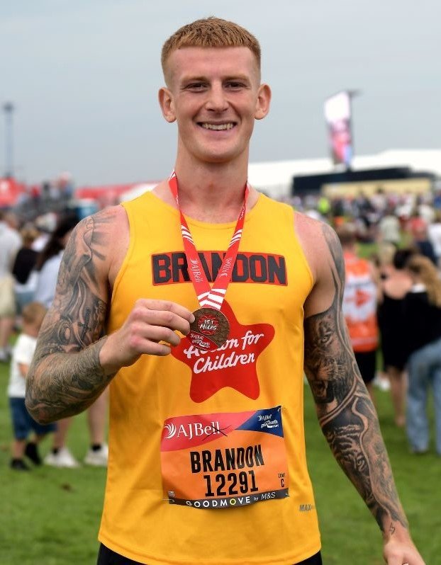 Man wearing Action for Children vest holding a medal after a race