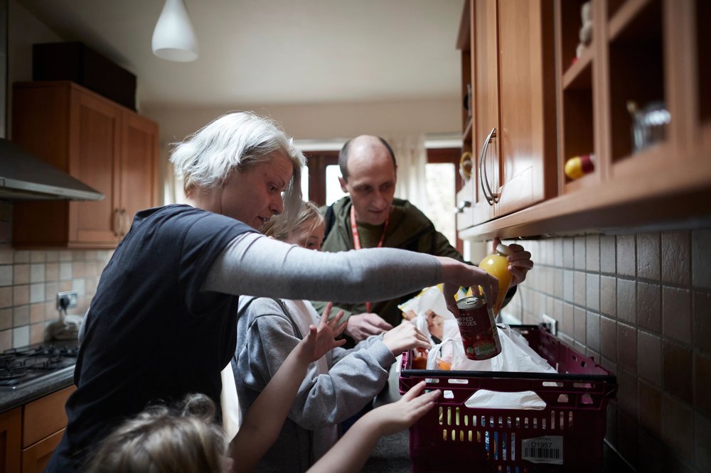 Family of four reaching into a food delivery package from Action for Children