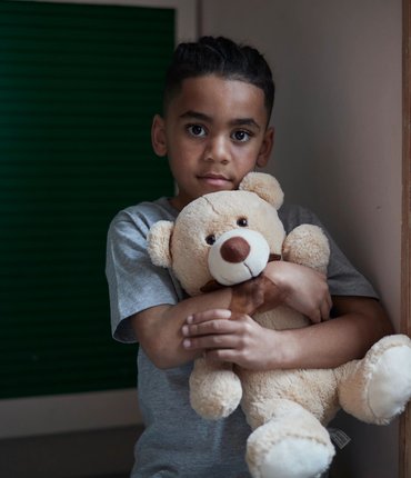 Boy looking into the camera holding a teddy bear