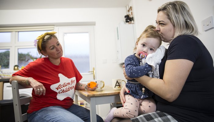 Natalia and Chloe sit at a kitchen table with Action for Children worker Kirsty