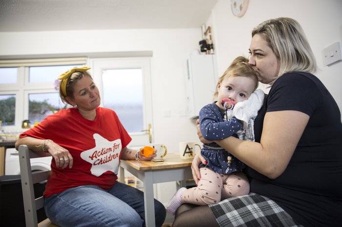 Natalia and Chloe sit at a kitchen table with Action for Children worker Kirsty