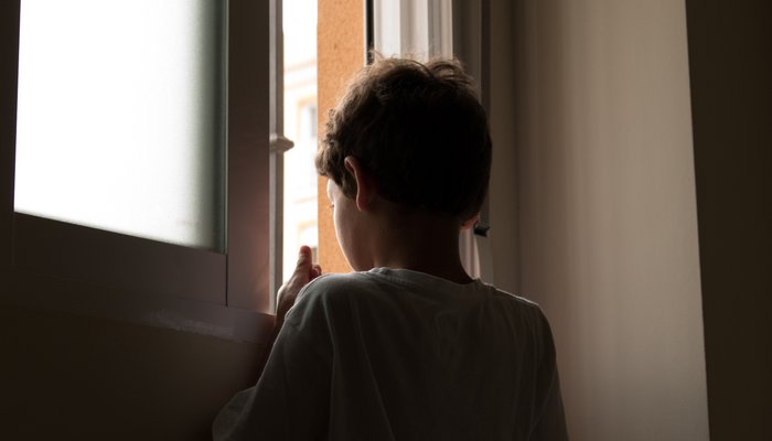 Back view of boy looking out of window