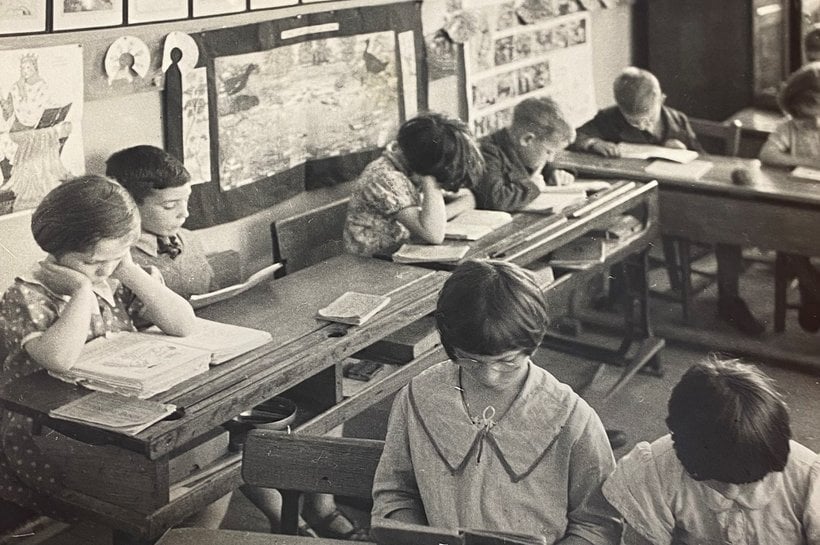 Black and white photograph of children writing at school