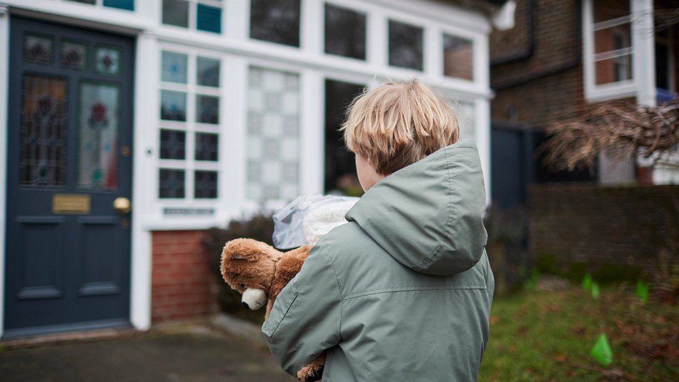 Boy carrying teddy approaching house