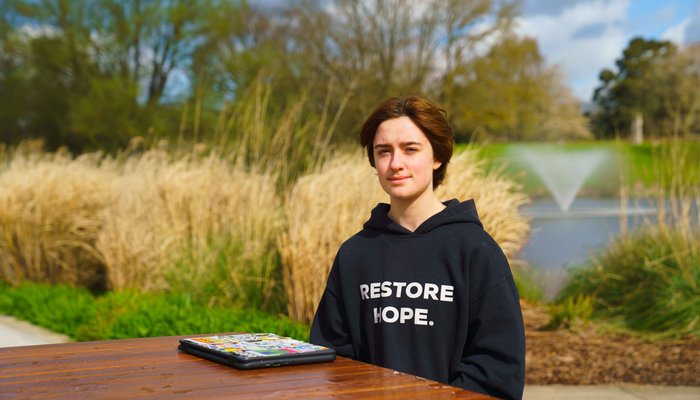Charlie sitting outside with water fountain behind