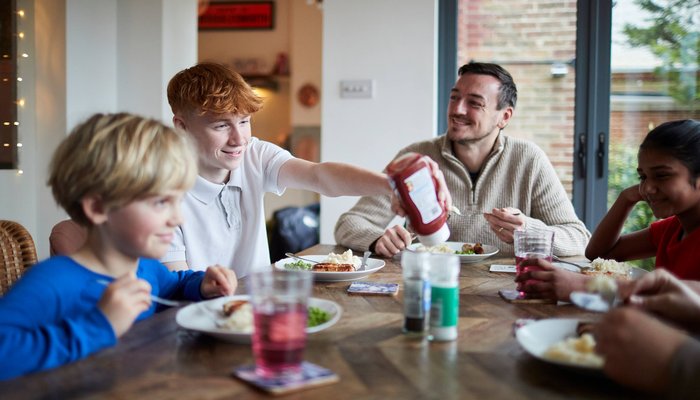 Children in care having breakfast with their carer and smiling
