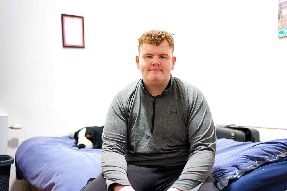 Christopher sitting on bed and smiling at camera