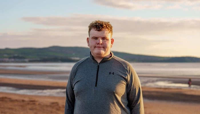 Christopher at the beach looking and smiling at the camera