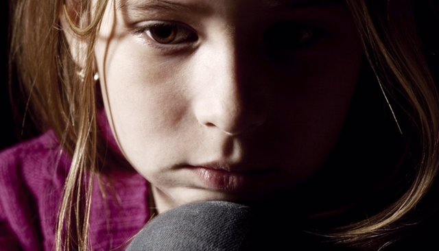 Close up of young girl looking worried with head resting on knee