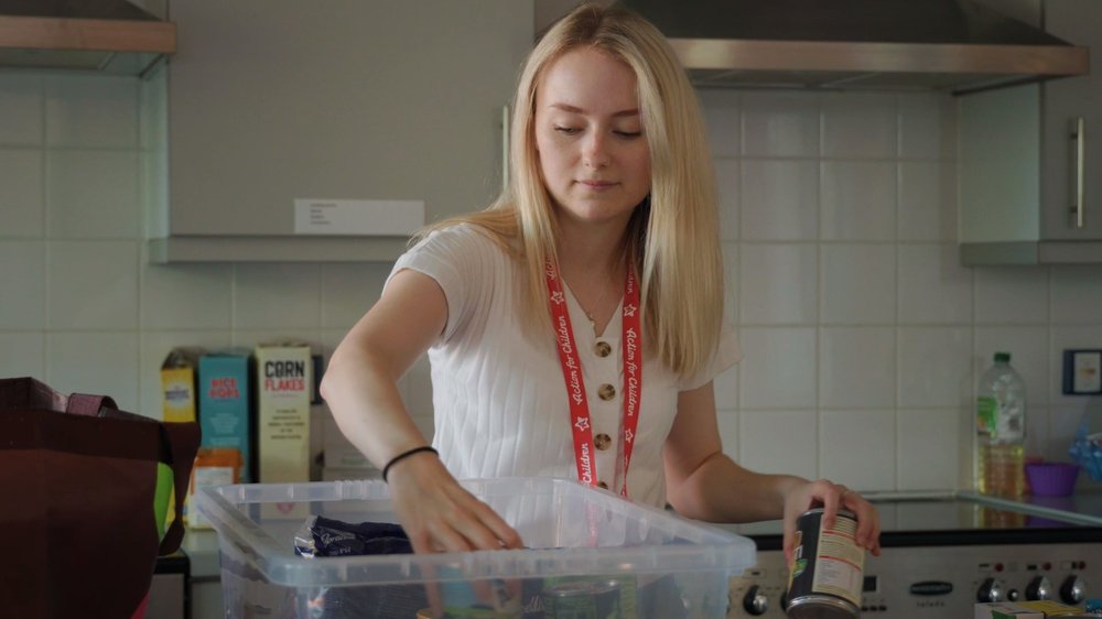 Courtney placing tinned food into a clear box