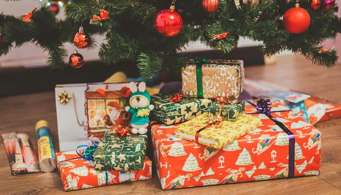 A stack of wrapped Christmas presents under a tree