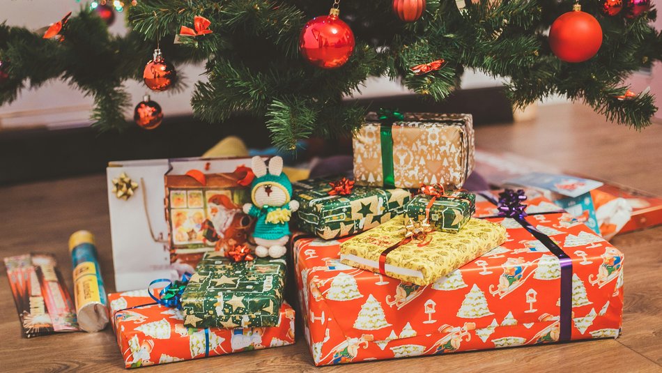 A stack of wrapped Christmas presents under a tree