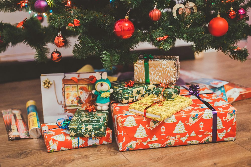 A stack of wrapped Christmas presents under a tree