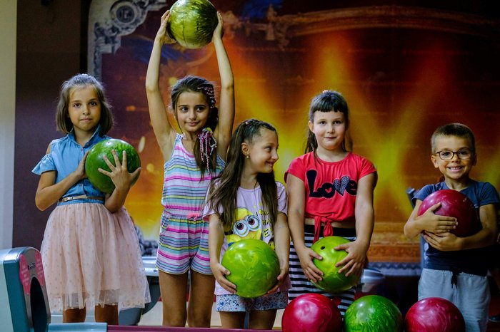 Group of children bowling with friends