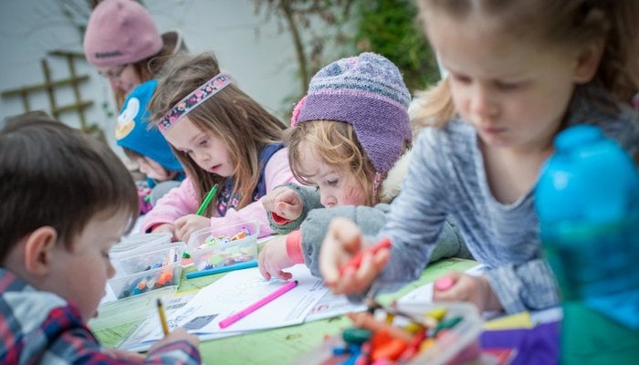 Giant wiggle children drawing masks around a table