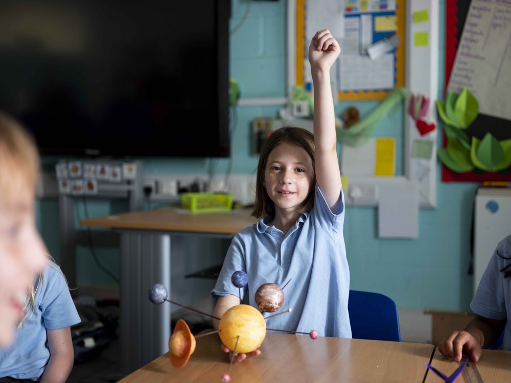 Girl in school uniform with raised hand.jpg