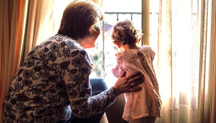 Grandma and grandchild looking out window.