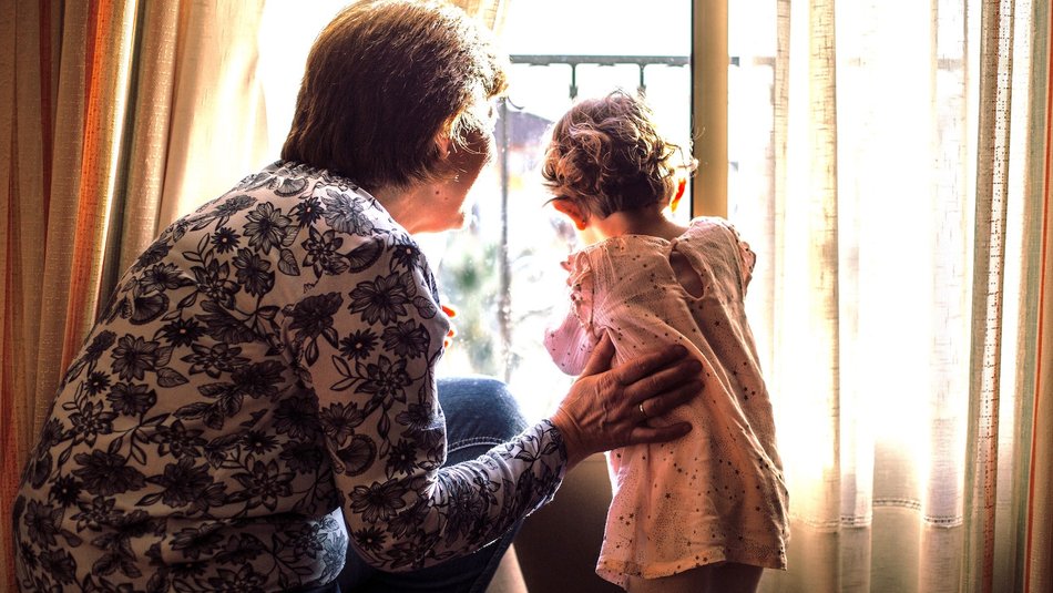 Grandma and grandchild looking out window.