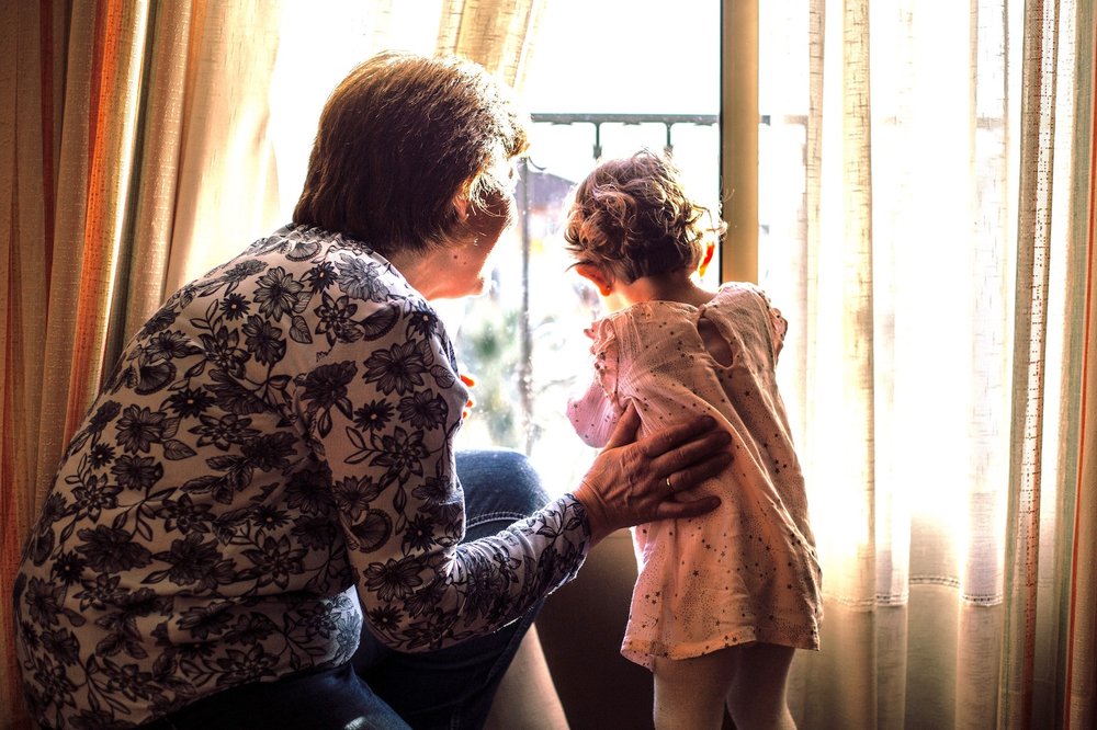 Grandma and grandchild looking out window.