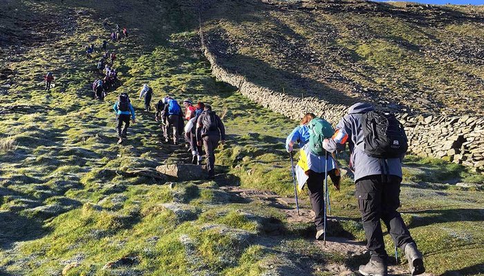 Group of hikers climb up a large hill