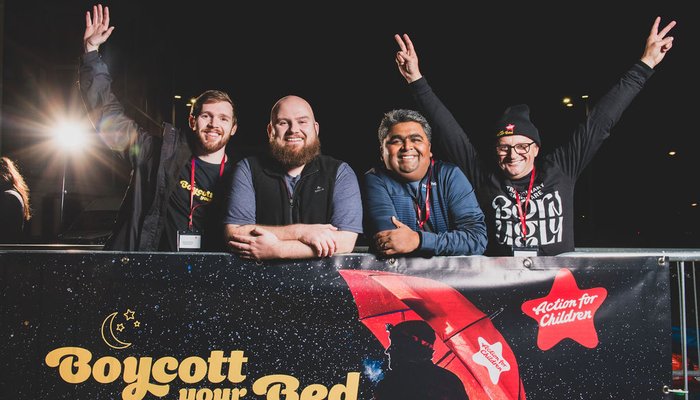 Group of men smiling above Boycott your Bed poster at Boycott your Bed's Leeds event