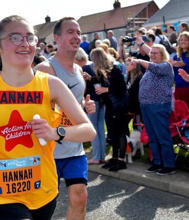 Hannah in a yellow Action for Children running vest at the Great North Run