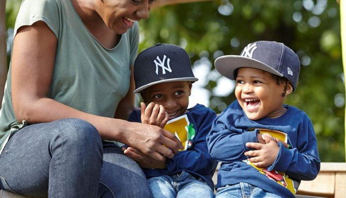 Happy mother and sons laughing and playing in the park