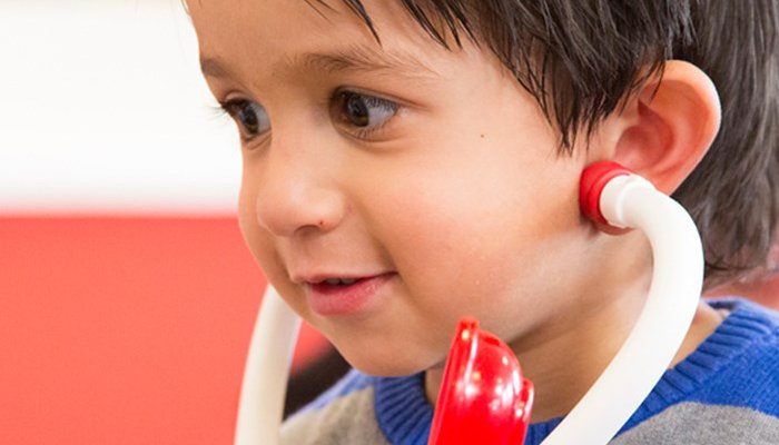 Happy young boy in school playing with toy stethoscope