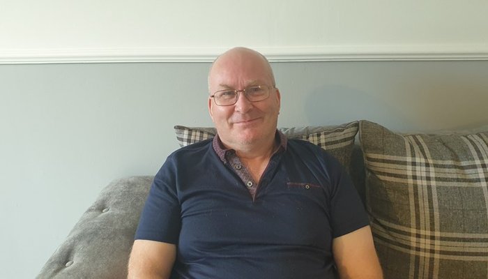 A male foster carer in his home smiling at the camera