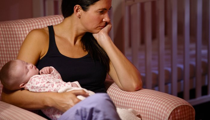 Sad tired mother holding baby