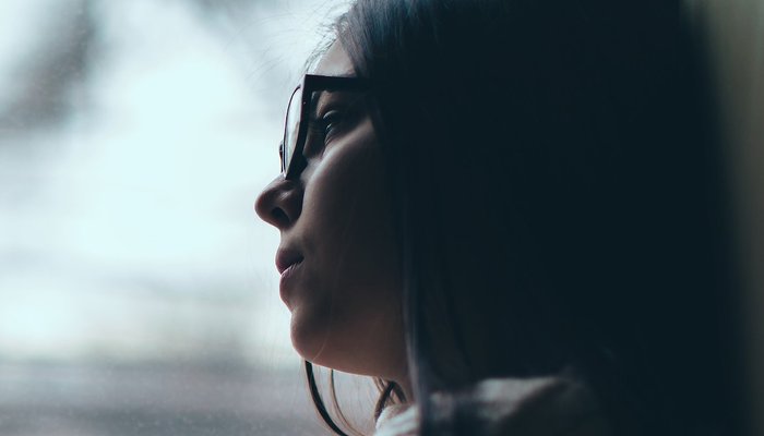 Sad teen girl looks out of the window