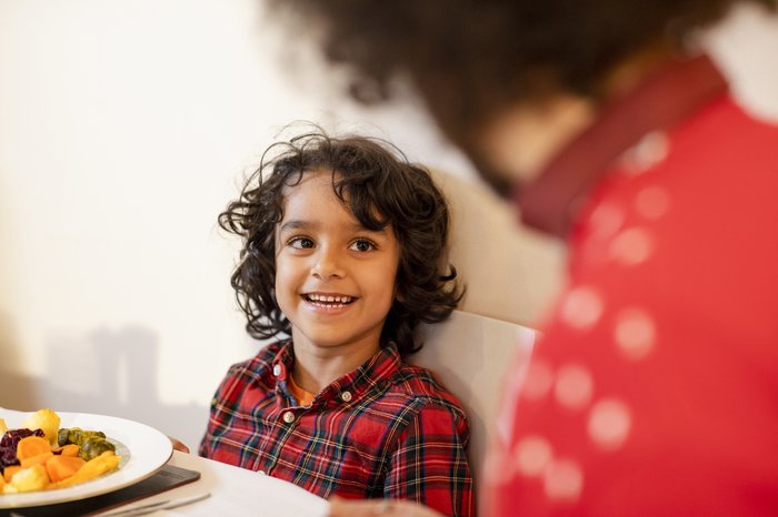 Little boy sitting at the Christmas dinner table smiling