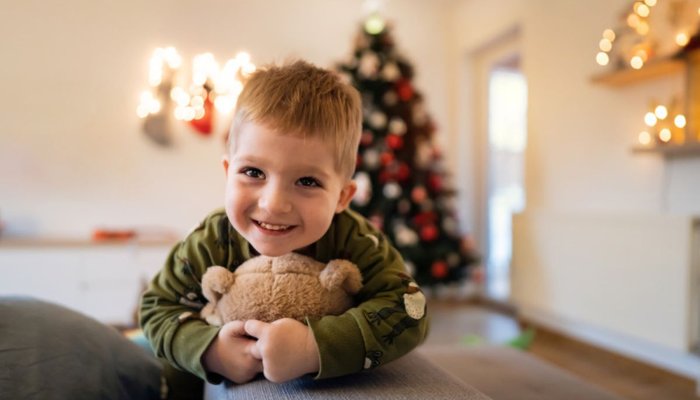 Little boy smiling with his teddy bear at Christmas