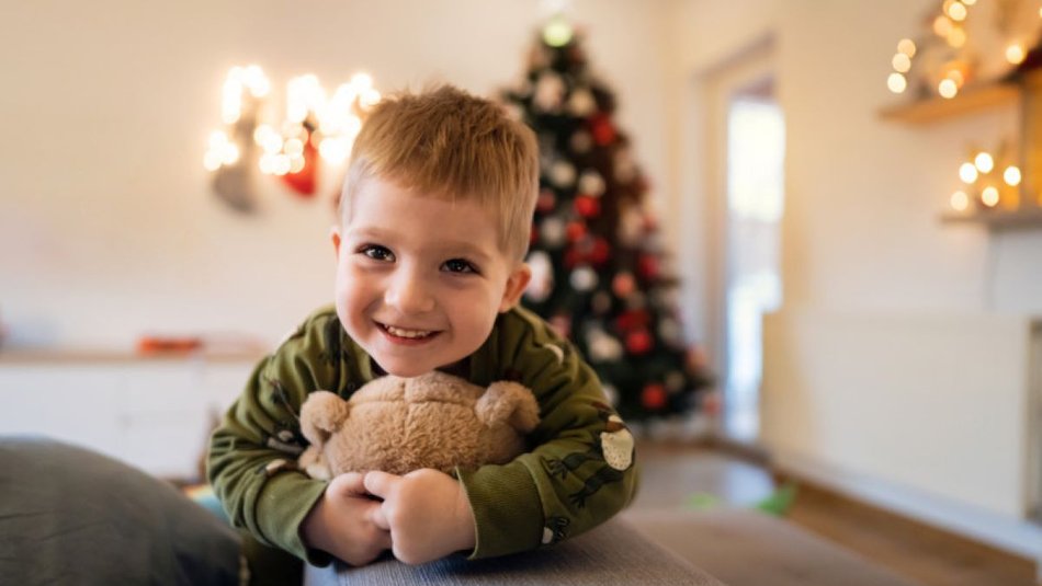 Little boy smiling with his teddy bear at Christmas