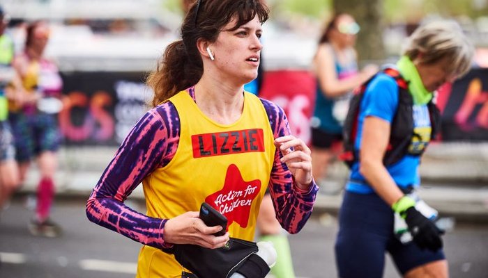 Woman running at the London Marathon wearing an Action for Children yellow vest