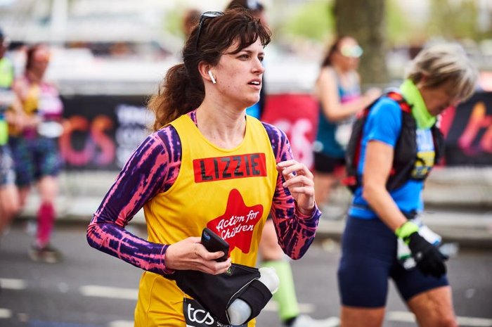 Woman running at the London Marathon wearing an Action for Children yellow vest