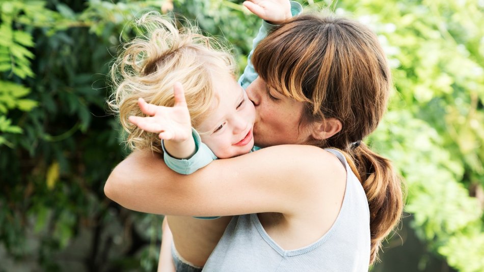 Mother kissing joyful son