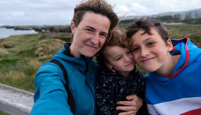 Mother taking a selfie with her two young sons outside in a field