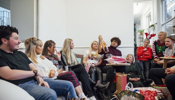 Office staff enjoying a Christmas party together, unwrapping gifts as part of secret Santa