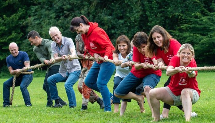 Foster families and Action for Children staff playing tug of war at an event