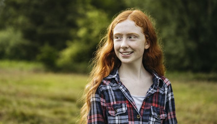 Outdoor portrait of smiling adolescent girl in woodland area