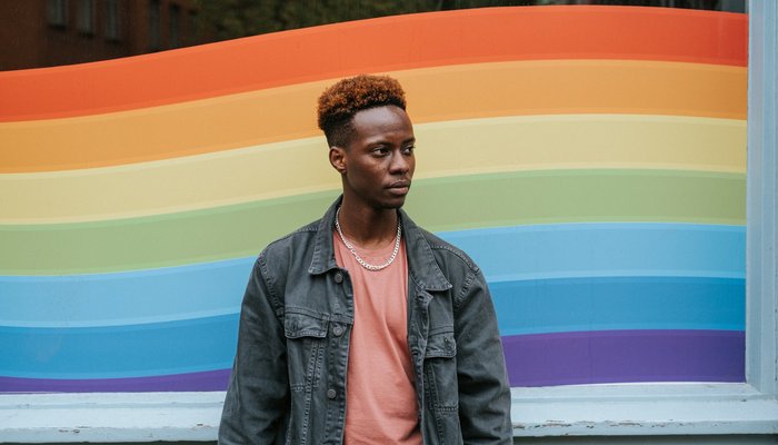 Black person in front of LGBT flag