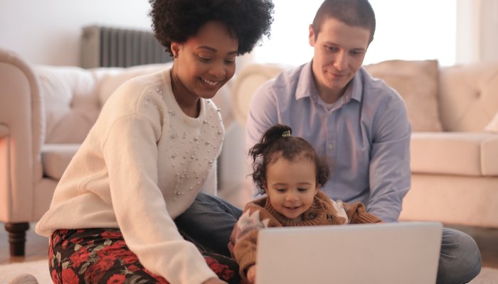 Photo of family sitting on floor using laptop close up