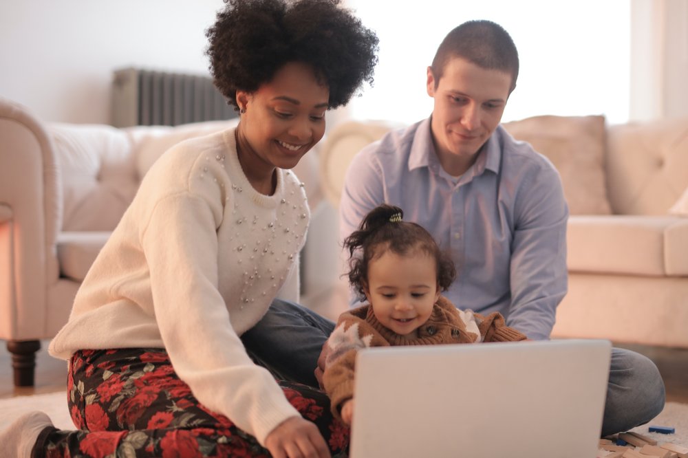 Photo of family sitting on floor using laptop close up