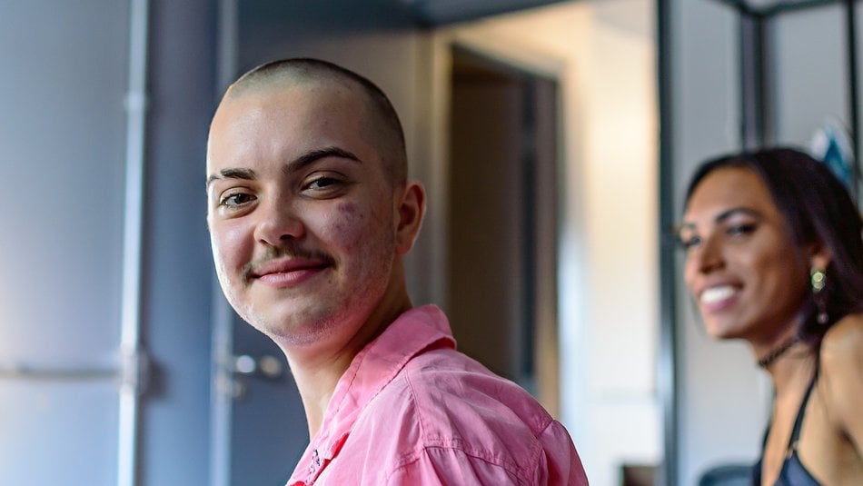 Portrait of a non-binary person smiling looking into the camwera and a transgender woman looking at the them